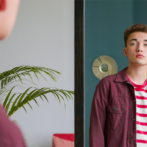 Joven mirando su reflejo en un espejo, en un momento de introspección